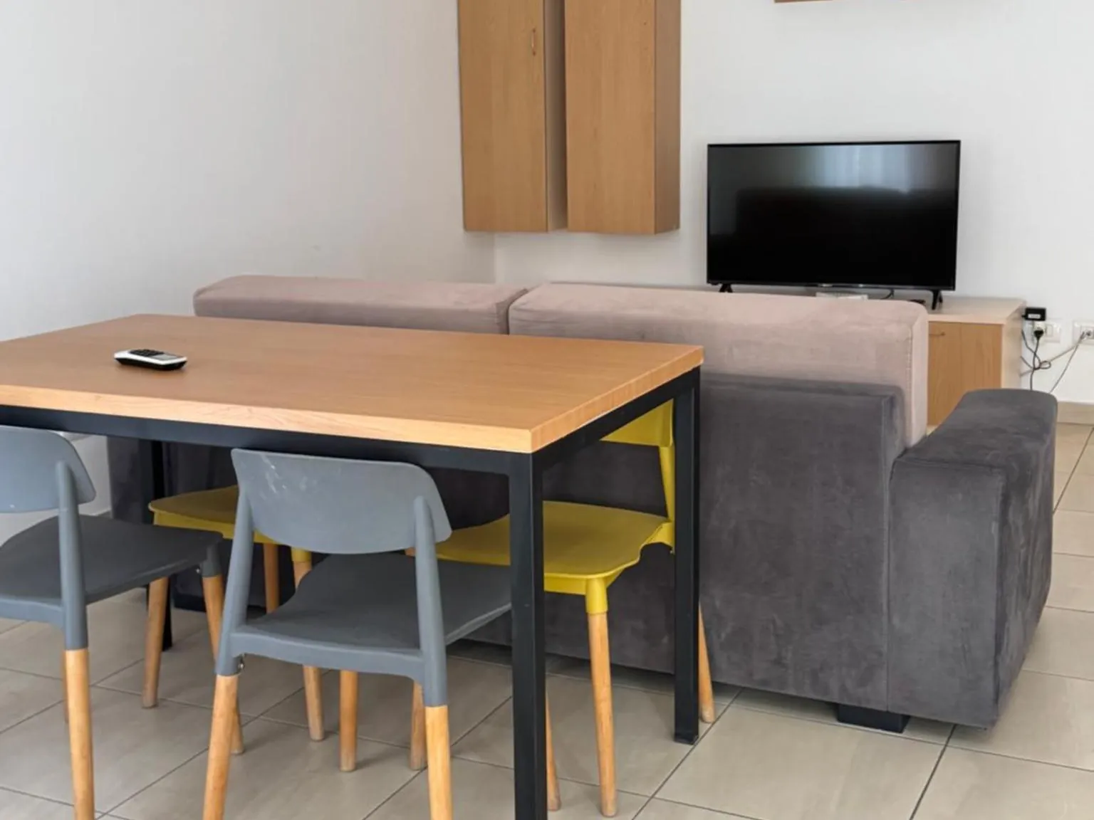 Living and dining area with sofa, table and TV in a one-bedroom apartment at Casa Italia, Tirana